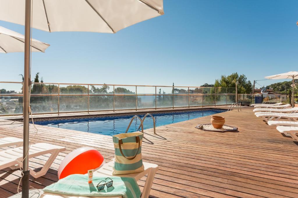 滨海托萨罗马纳皮尔假期别墅酒店的木制甲板上配有椅子和遮阳伞的游泳池