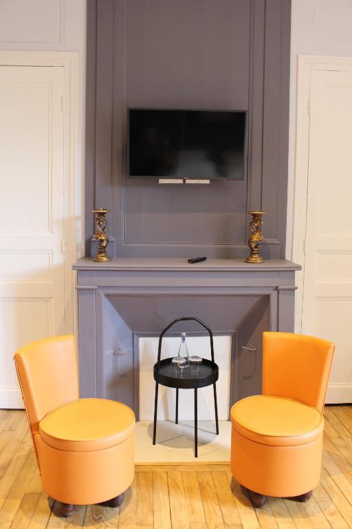 Saint-ÉvarzecHôtel Les Empreintes的客厅配有两把椅子和壁炉