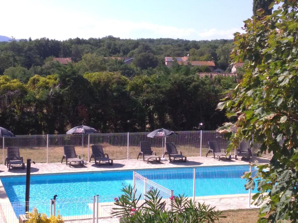 沃格于埃LES VOYAGEURS的围栏旁带椅子和遮阳伞的游泳池