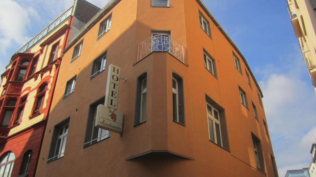 科隆Hostel Heinzelmännchen的一座高大的橙色建筑,上面有时钟