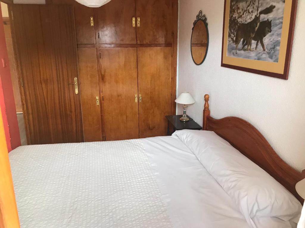 福米加尔Apartamento céntrico en Formigal的卧室配有白色的床和木制橱柜。