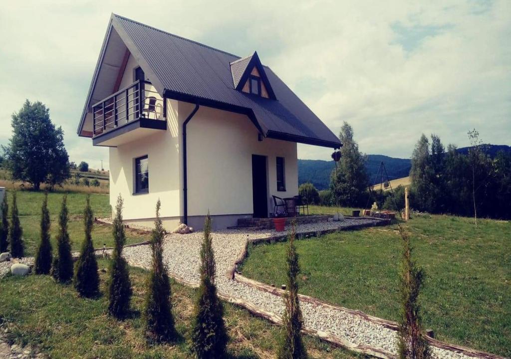 GrywałdDomek na Przylasku的白色的小房子,在田野里设有阳台