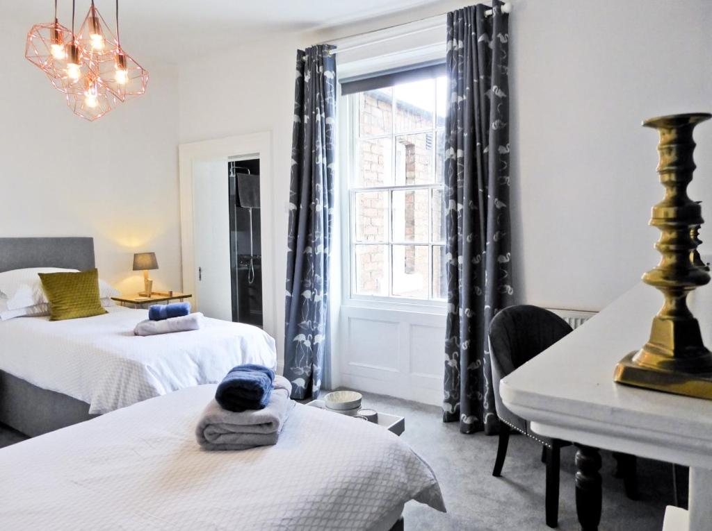 卡莱尔Rosalind House的一间卧室设有两张床、一张桌子和一个窗口。