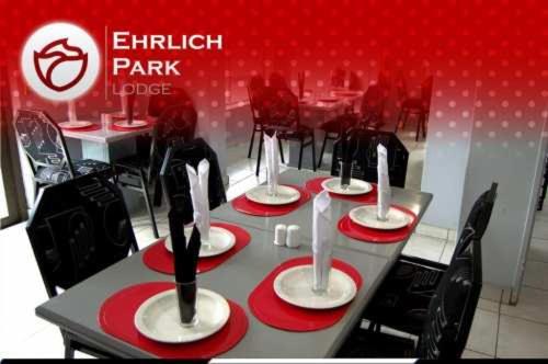 布隆方丹Ehrlichpark Lodge self catering and spa的餐厅的桌子,上面有红白板和椅子
