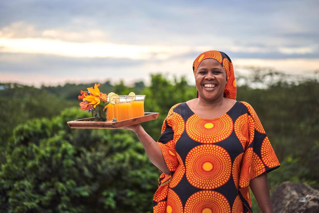 育空河Hillside Retreat – Africa Amini Life的拿着饮料和鲜花的女人