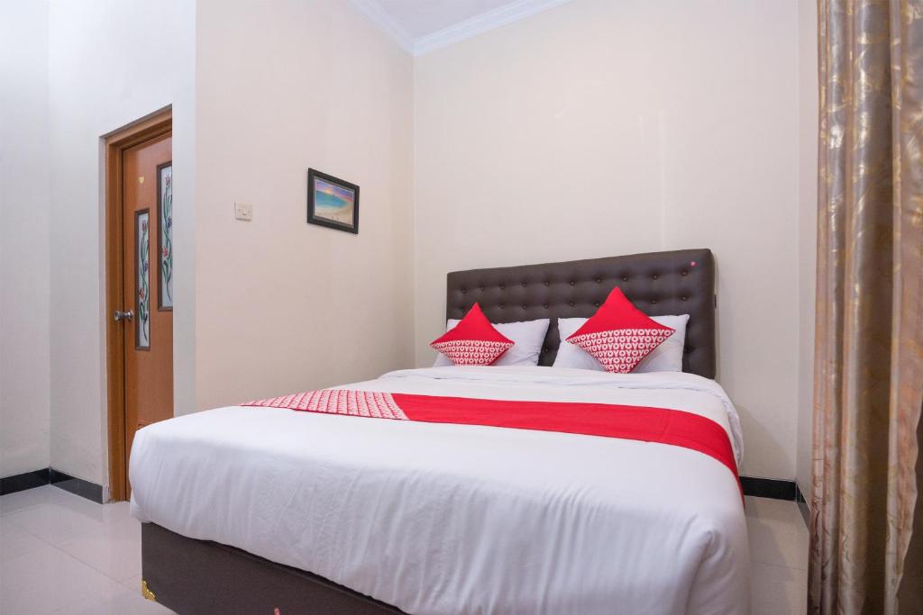日惹OYO 1226 Al Abror Homestay的一间卧室配有一张带红色枕头的大床