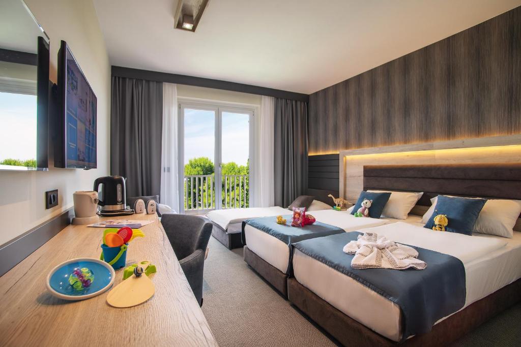 伊佐拉Hotel Haliaetum - San Simon Resort的酒店客房设有两张床和电视。