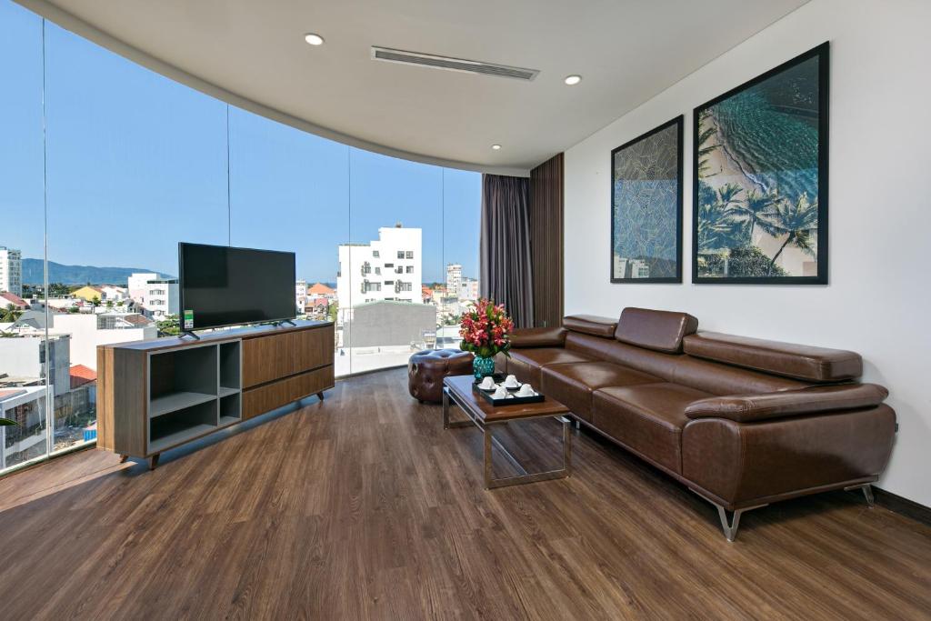 岘港Meliora Hotel & Apartment的客厅配有棕色真皮沙发和电视