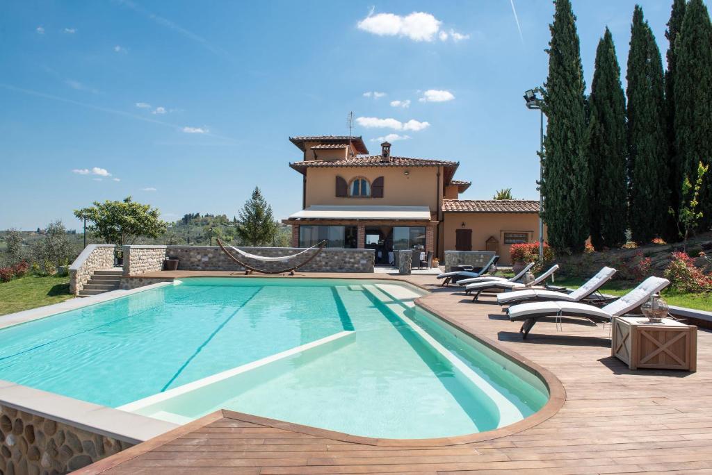 蒙泰斯佩尔托利Agriturismo Casale Ugolini的一个带椅子的游泳池以及一座房子