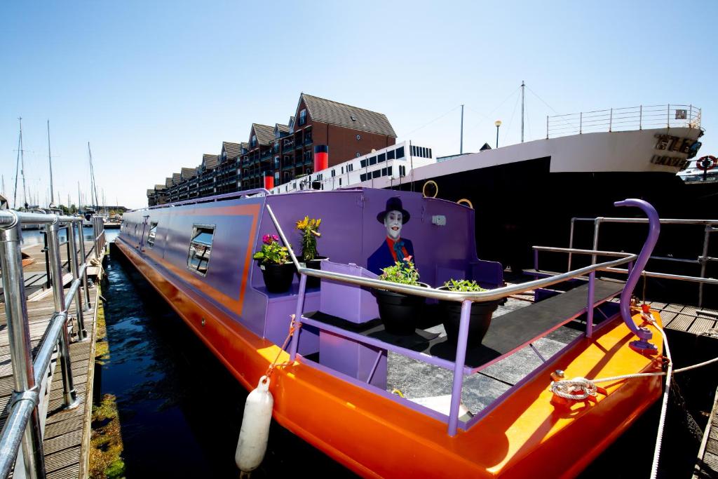 利物浦捷克博特酒店的一艘橙色和紫色的船停靠在船旁