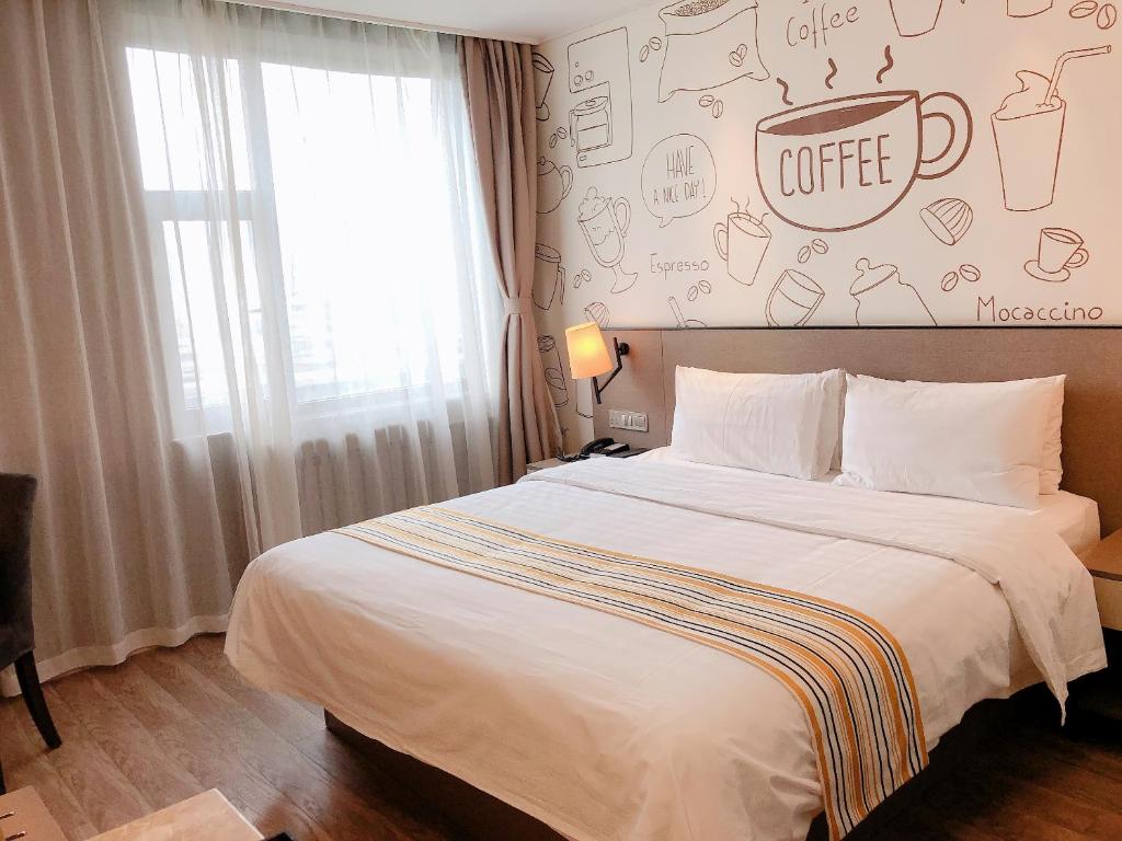 兰州如家精选酒店兰州张掖路步行街店的卧室配有一张大床,墙上挂有咖啡标志