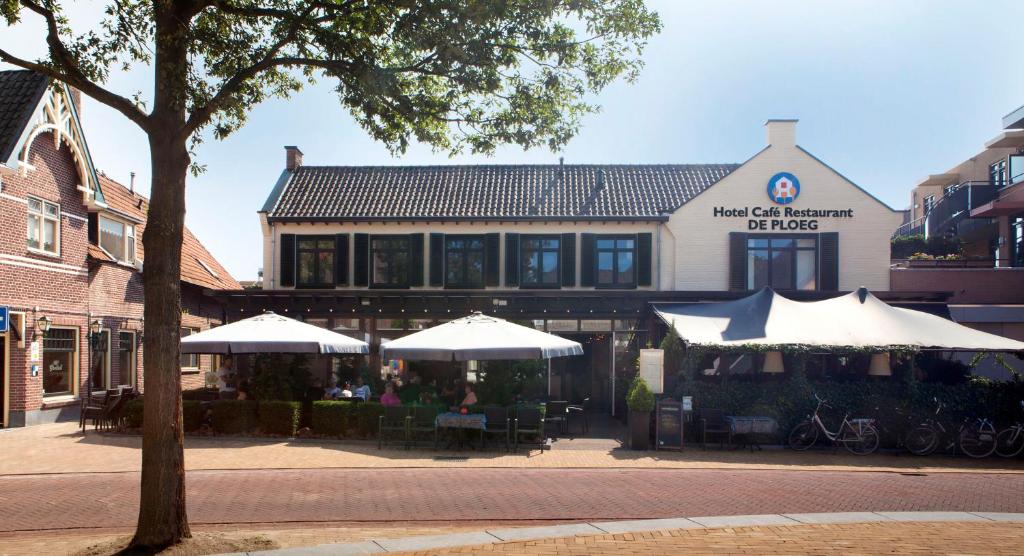 Varsseveld德普罗格霍恩餐厅酒店的前面有桌子和伞的建筑