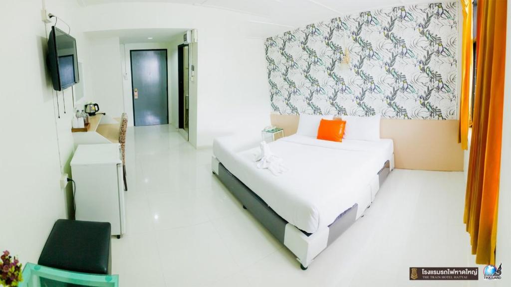 合艾The Train Hotel Hatyai的白色的客房配有床和电视。