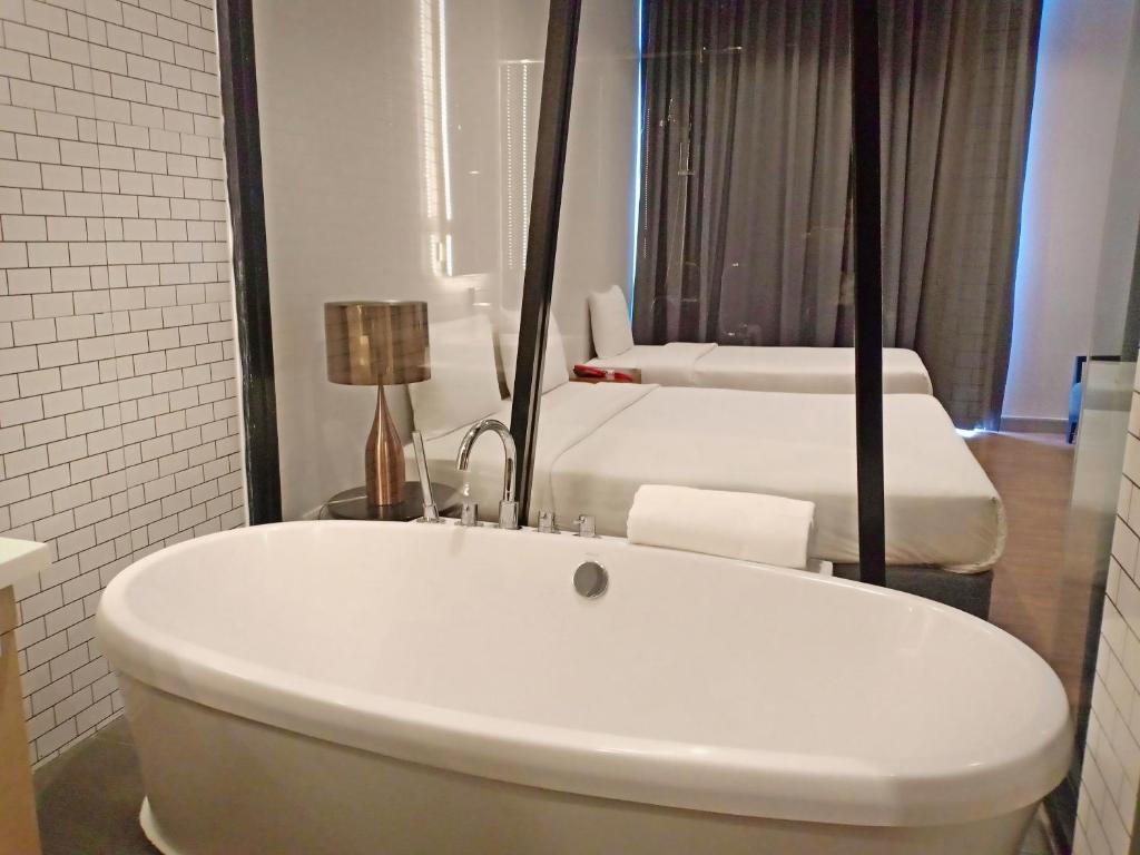 莱卡邦Vismaya Suvarnabhumi Hotel的浴室设有2张床和白色浴缸。