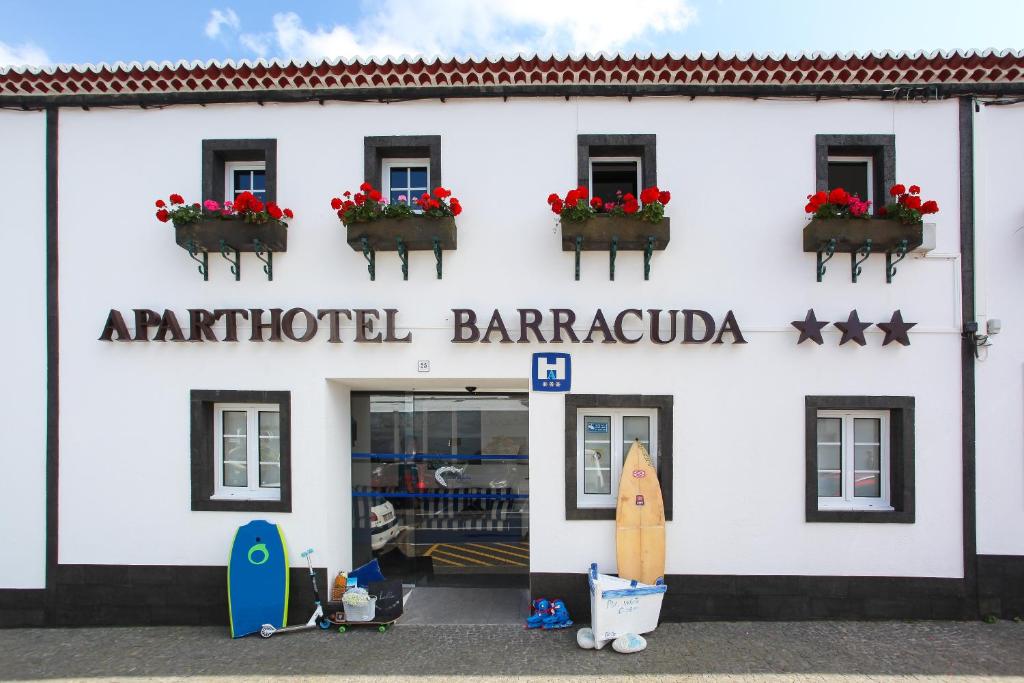 蓬塔德尔加达Aparthotel Barracuda的前面有冲浪板的白色建筑