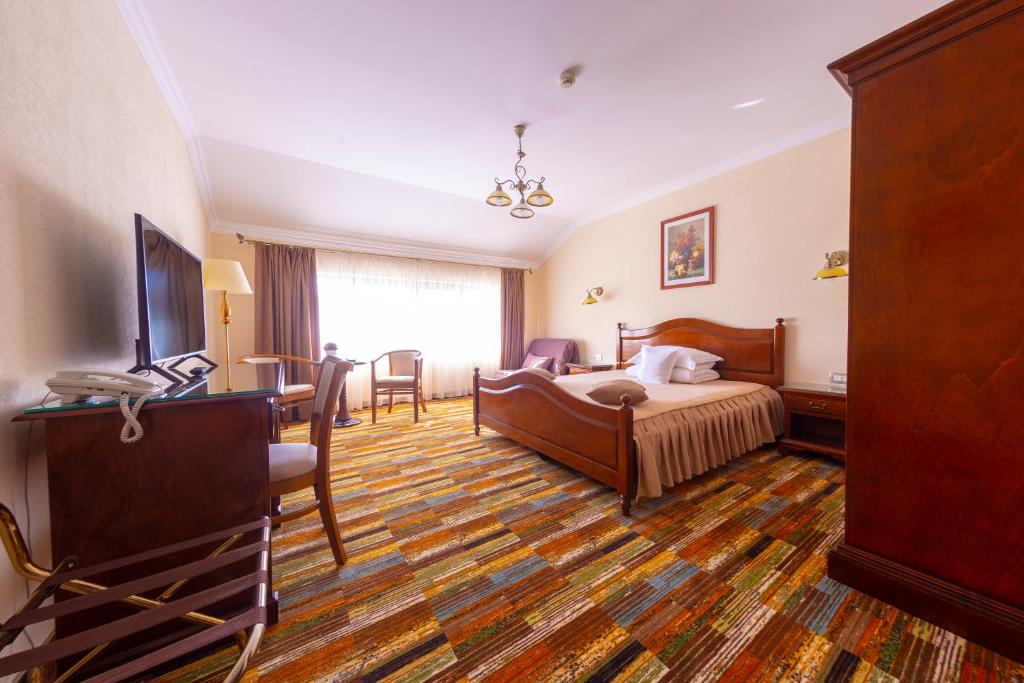 阿尔巴尤利亚Vila Preciosa的酒店客房带一张床、一张桌子和椅子