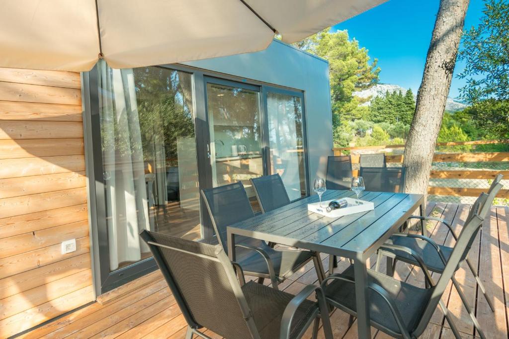 马卡尔斯卡Apartments and Mobile Homes Makarska的房屋甲板上的桌椅