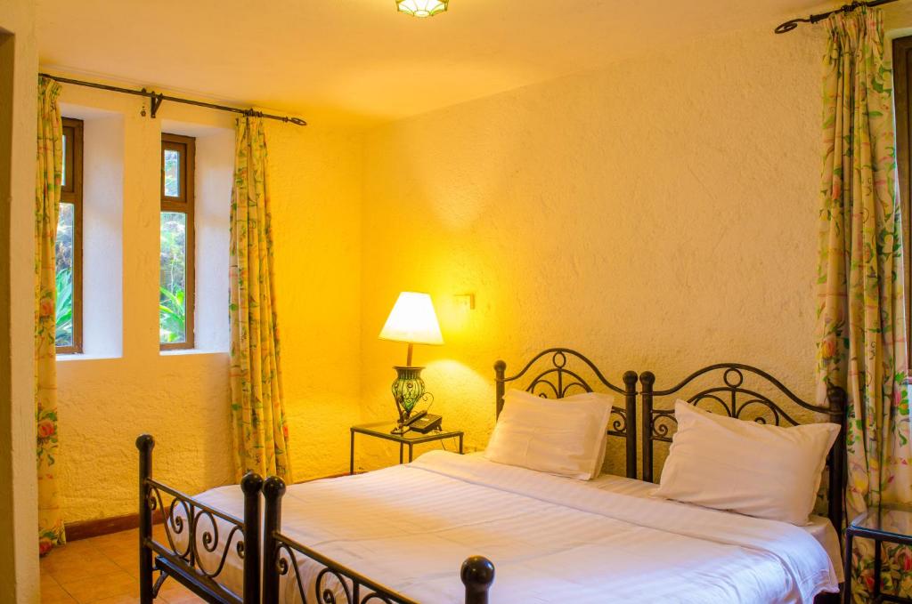 奈瓦沙Kianderi Villa-Great Rift Valley Resort的一间卧室配有一张带白色床单和一盏灯的床。