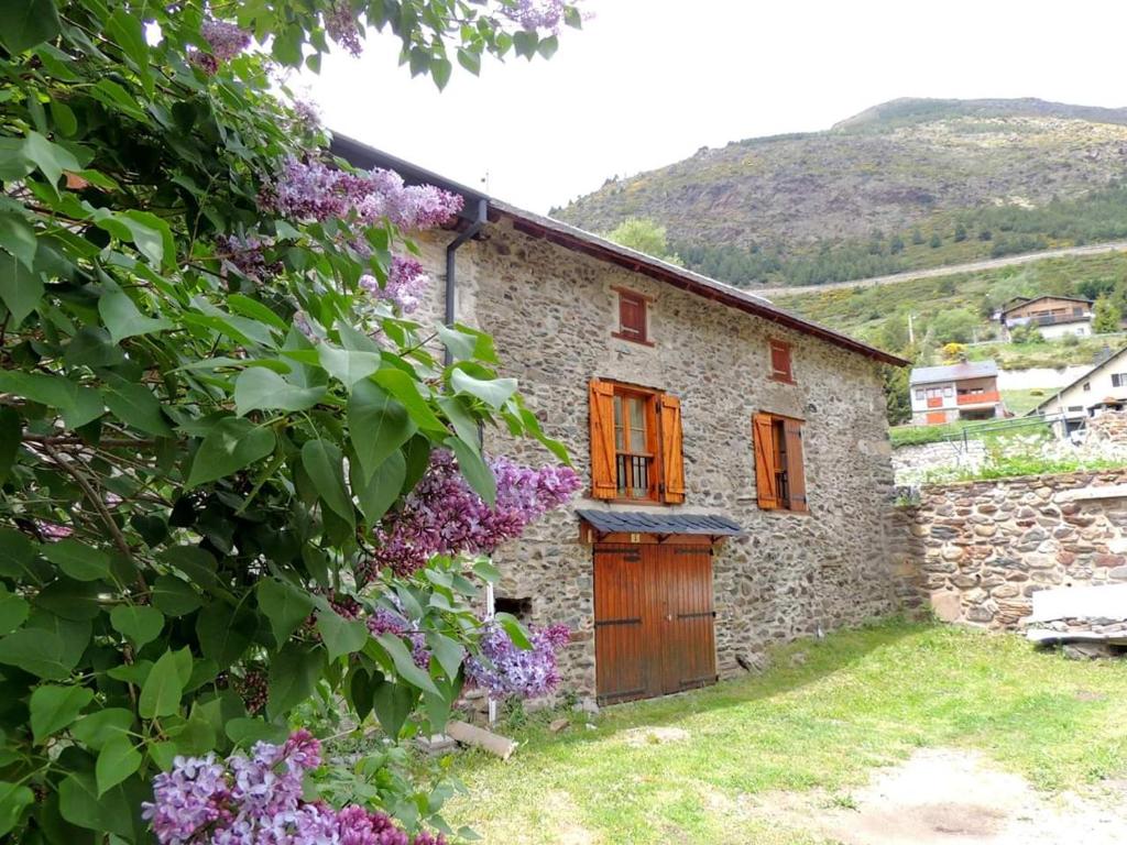 波泰皮莫朗Montagne Ski Porté Puymorens GÎTE的石头房子,带木门和紫色花