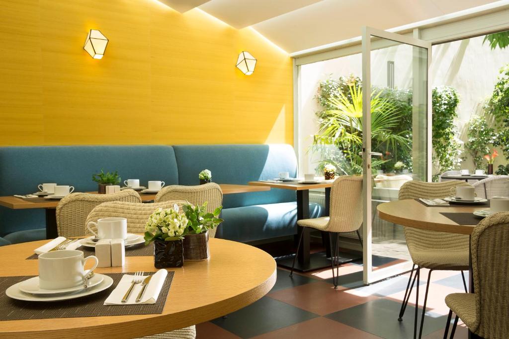 巴黎艺术家别墅酒店的餐厅设有桌椅和窗户。