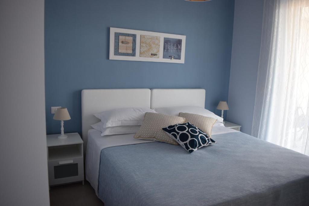 圣泰雷萨迪里瓦Casa Vacanze Lombardo的一间卧室拥有蓝色的墙壁,配有一张带枕头的床。