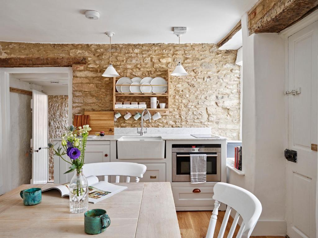 奇彭纳姆Artisan Cottage的厨房配有木桌和白色橱柜。