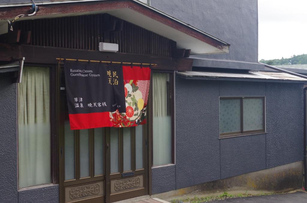 草津Kusatsu Onsen Guesthouse Gyoten的一面有横幅的建筑物