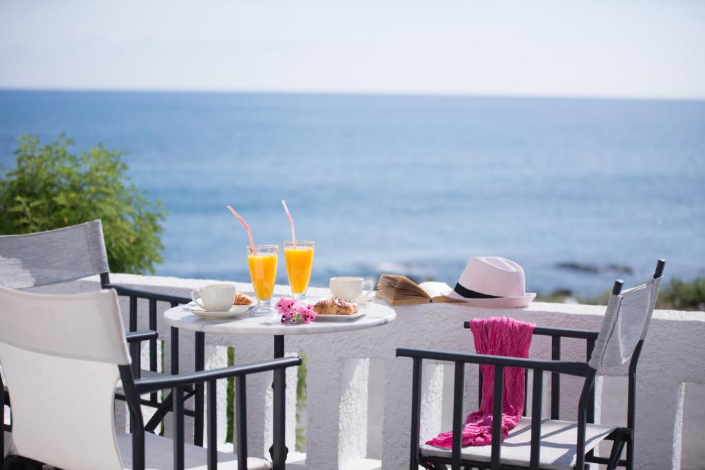 赫索尼索斯阿伦海滩公寓式酒店的一张桌子、两把椅子和一张桌子,并备有饮料