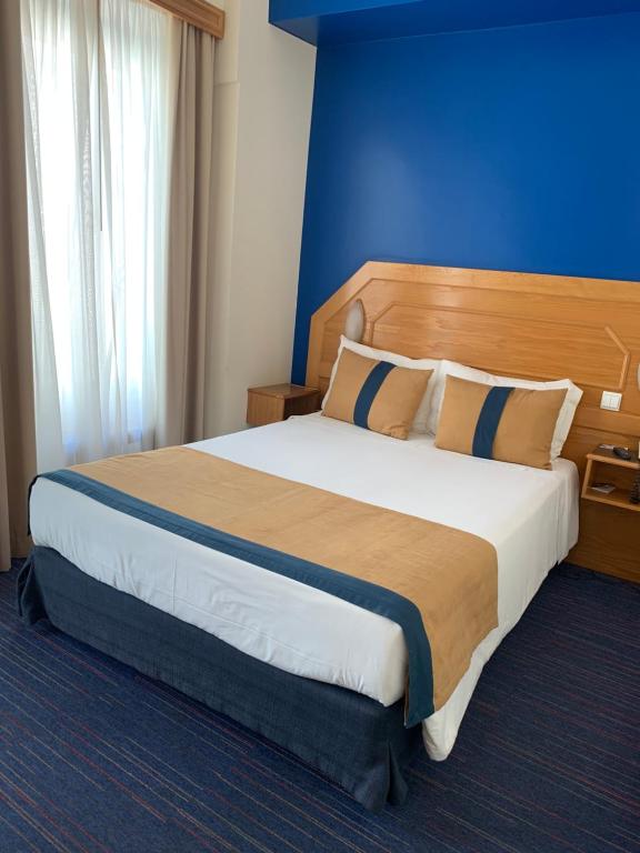 里斯本智利多之栈酒店的一间卧室设有一张蓝色墙壁的大床