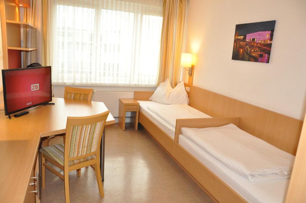 林茨科尔平林茨旅舍的客房设有两张床、一张桌子和一台电视。