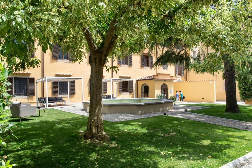 佛罗伦萨霍尔多修道院酒店的一座有游泳池的建筑,位于一个树木繁茂的庭院内