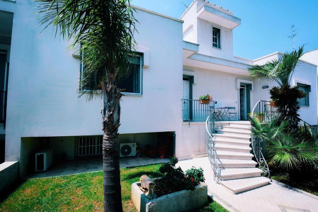 韦列Casa PARADISO Camere in Affitto的白色建筑前的棕榈树