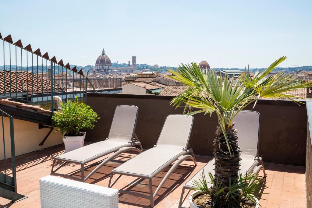 佛罗伦萨佛罗伦萨普鲁斯酒店的阳台配有椅子,屋顶上种植了棕榈树