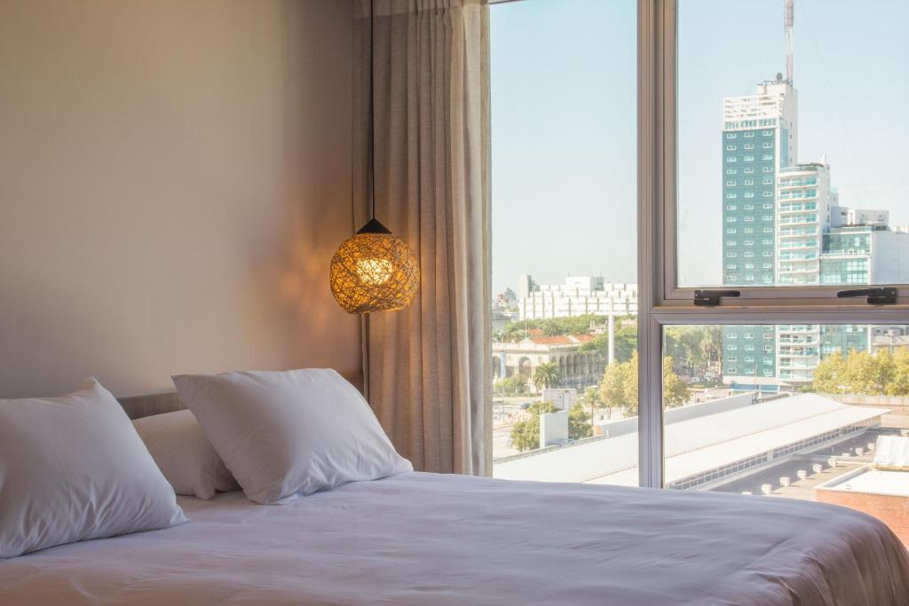 蒙得维的亚Hotel Ciudadano Suites的一间卧室设有一张床和一个大窗户