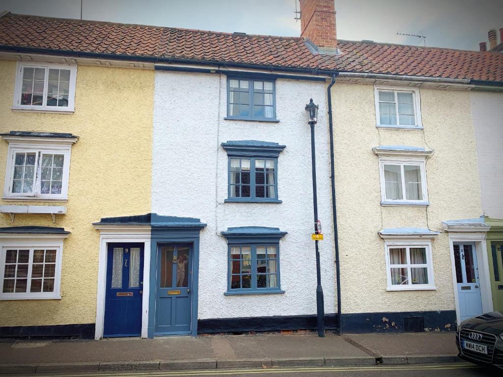 贝里圣埃德蒙兹Sweet & cosy 10 Bridewell Cottage with parking available upon request的黄色和白色的房子,设有蓝色的门窗