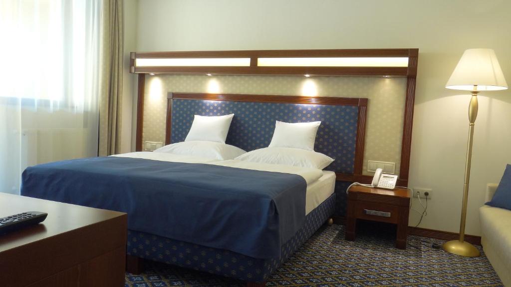德布勒森森特鲁姆酒店的一间卧室配有一张带蓝色毯子的大床