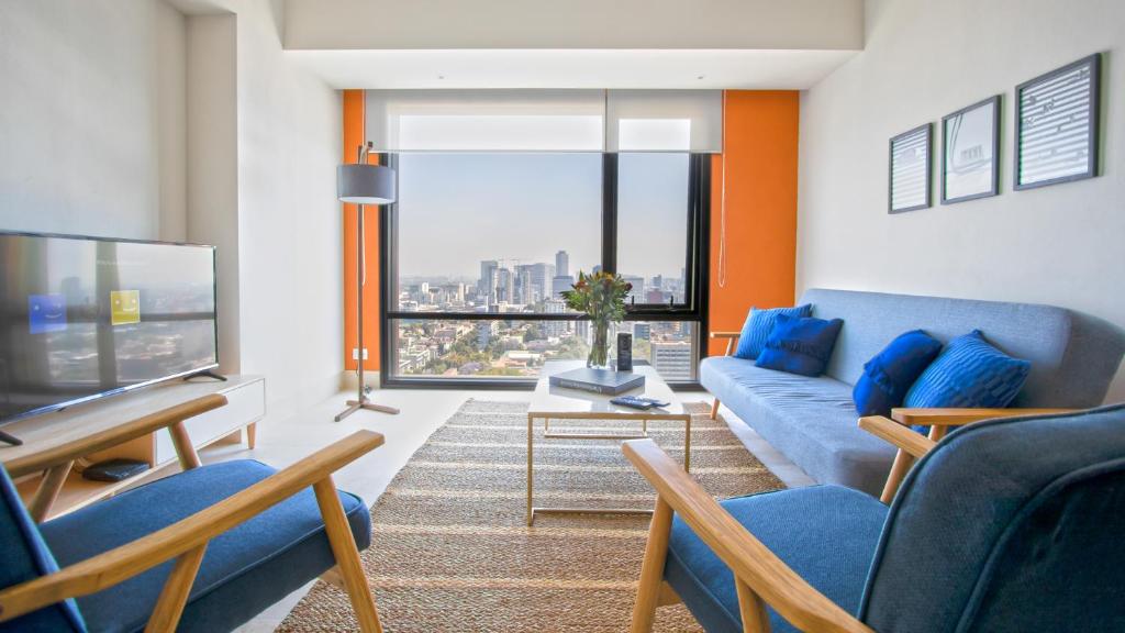 墨西哥城Miyana Condos by LiveMexicoCity的客厅设有蓝色的沙发和大窗户
