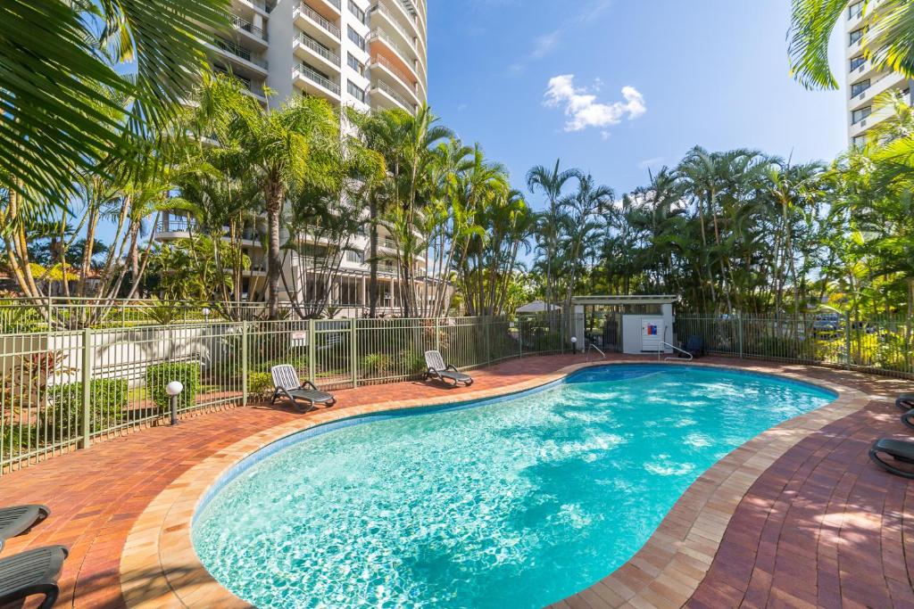 黄金海岸The Meriton Apartments on Main Beach的一个带两把椅子的游泳池,棕榈树
