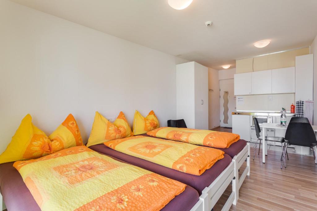霍其多夫Anstatthotel Hochdorf - self-check-in的一间卧室配有两张带橙色和黄色枕头的床