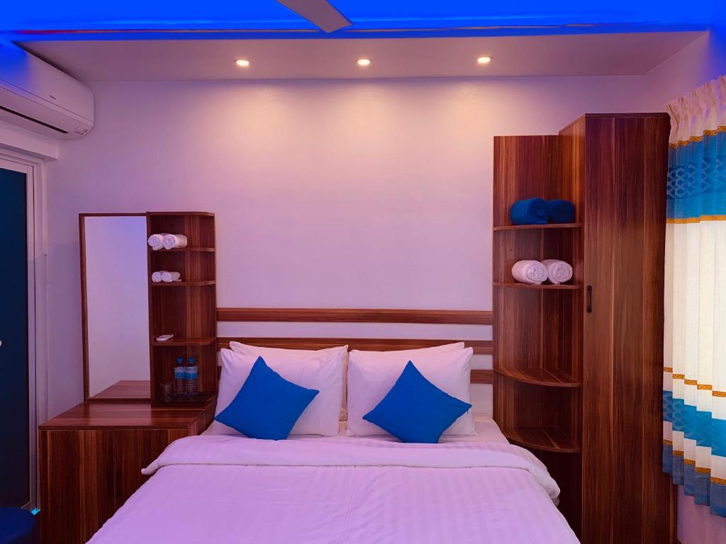 OmadhooHudhuvelimaldives的一间卧室配有一张带蓝色枕头的大床