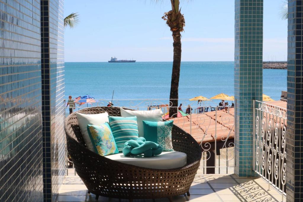 福塔莱萨Sonho de Iracema Hostel Boutique的俯瞰海滩的阳台上的藤椅