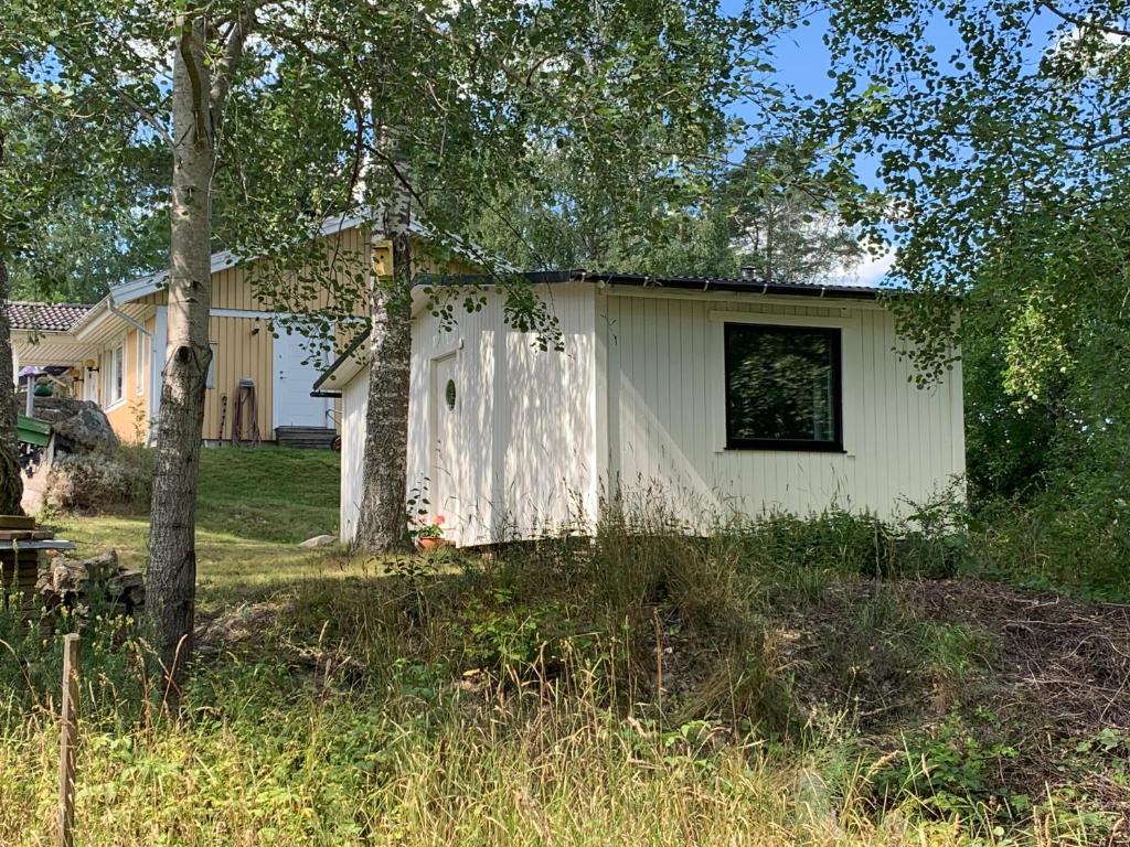 HölöThe Little Swedish Stuga的一座白色的小房子,拥有窗户和树木