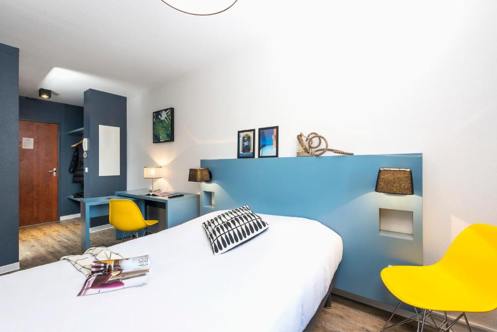 波尔多Ténéo Apparthotel Bordeaux - Gare Saint Jean的卧室配有白色的床和黄色的椅子