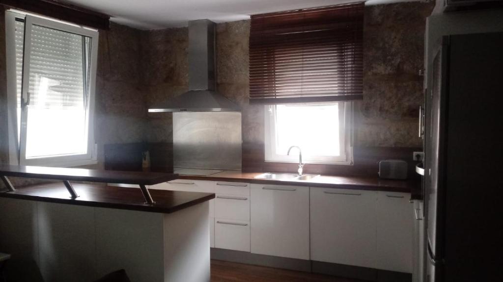 马林Casa Urbana en Marín的厨房配有白色橱柜、水槽和2扇窗户。
