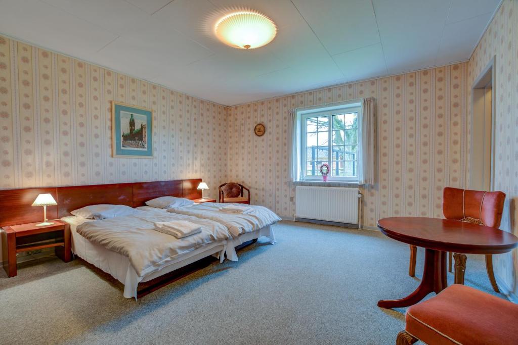 岑讷Abild Kro & Hotel的一间卧室配有一张床、一张桌子和一个窗户。