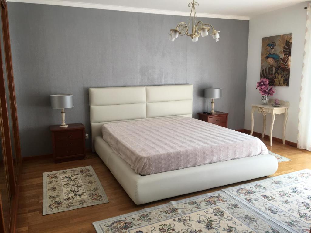 纳扎雷Moradia Chicharro的卧室配有一张白色床、两张桌子和两张地毯。