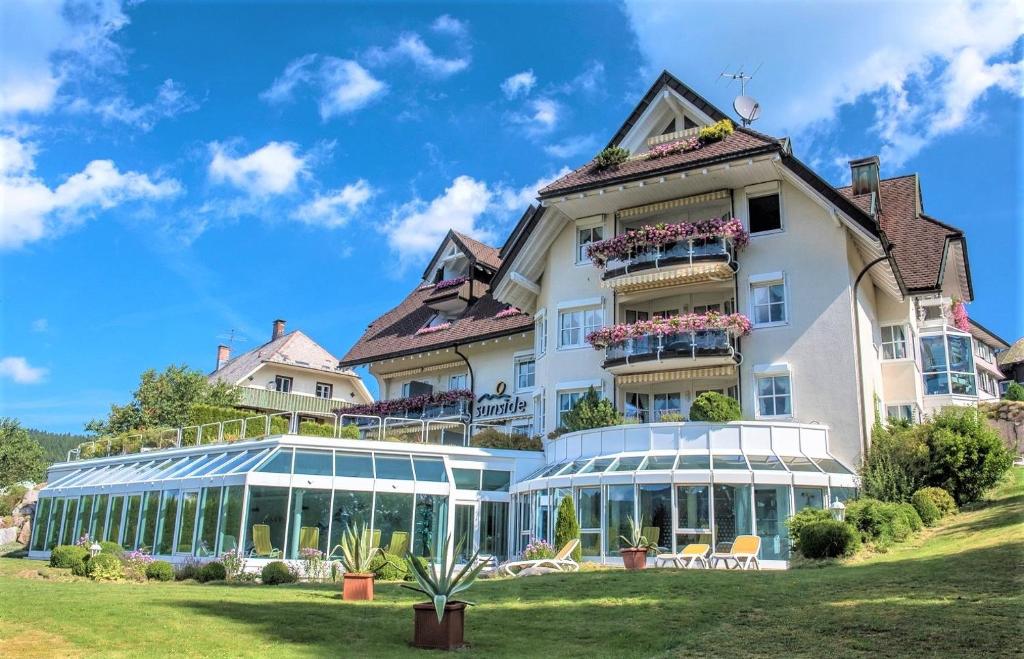 施卢赫湖Villa Sunside Appartements und Ferienwohnungen Schluchsee的一座带温室的大型白色建筑