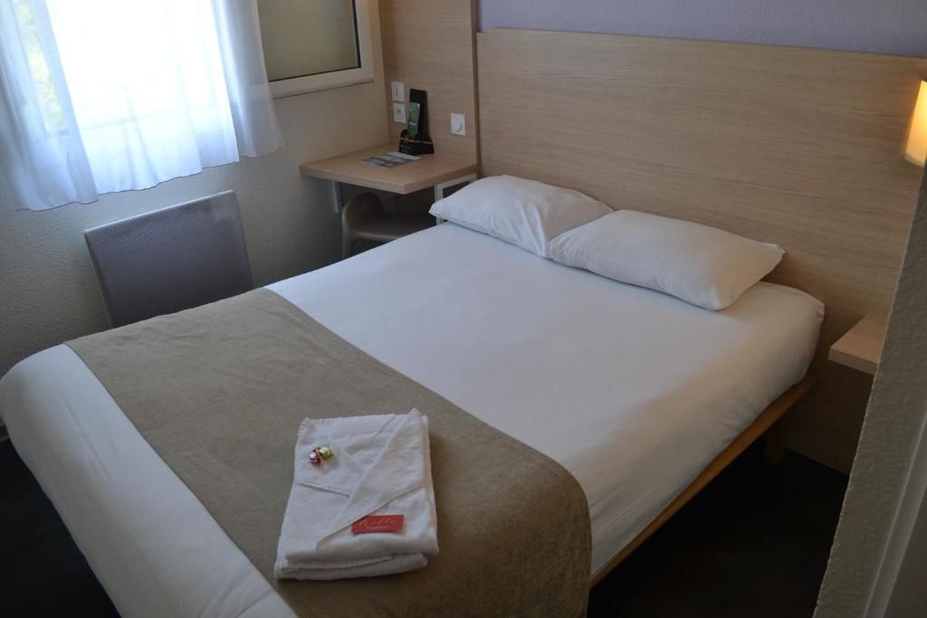 瑟农方程式俱乐部酒店的一间酒店客房,配有一张带毛巾的床