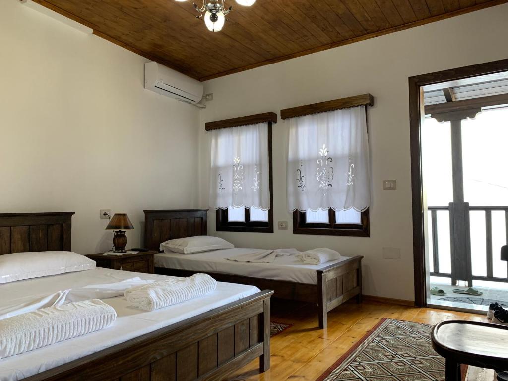 培拉特Guest House Genti的带2张桌子和窗户的客房内的2张床