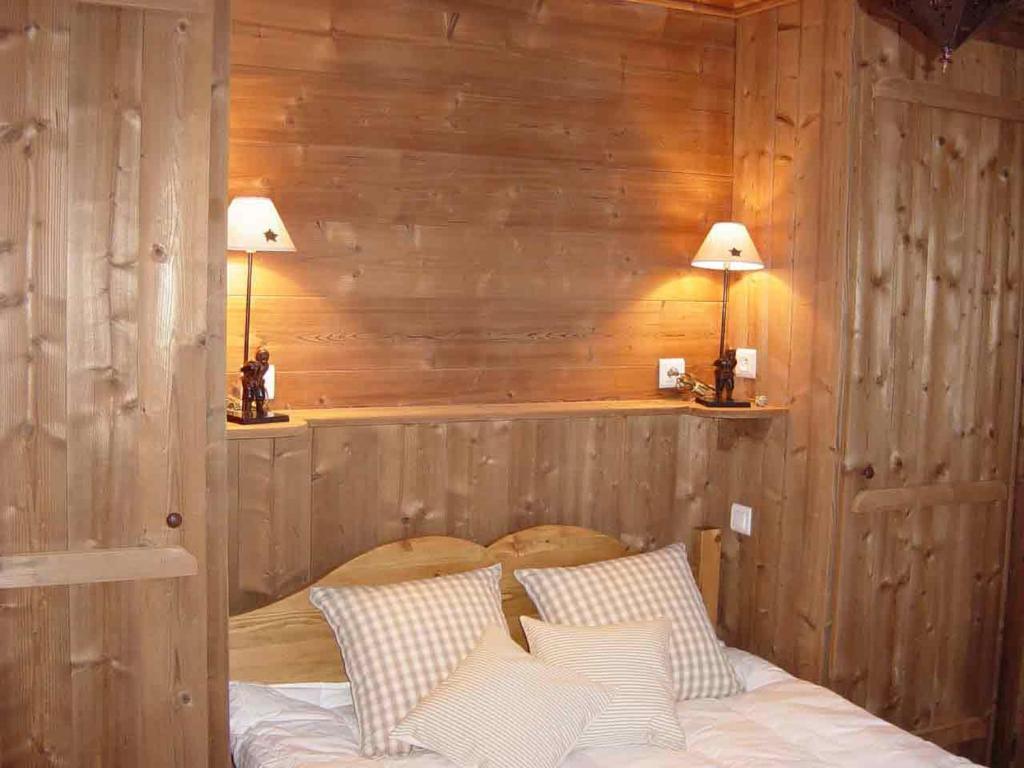 蒂涅Le Pramecou Tignes Val Claret的一间卧室设有木墙和一张带枕头的床。
